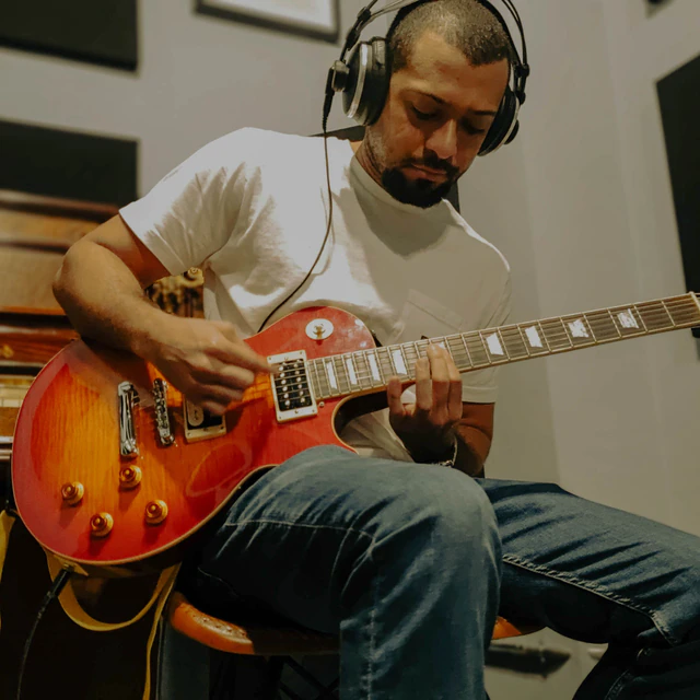 Un guitarrista grabando con auriculares en el estudio